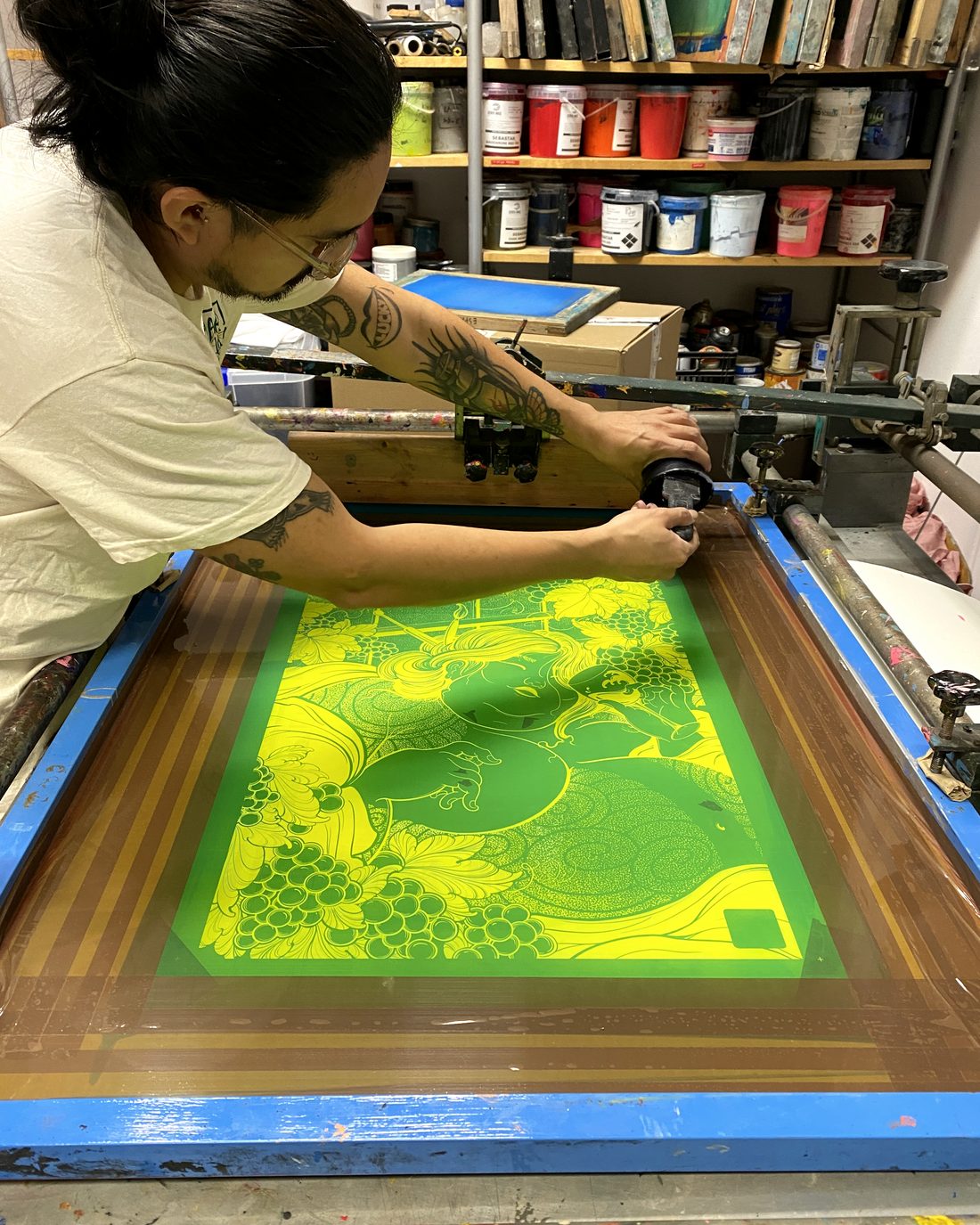 Imprimiendo a mano en la pantalla de serigrafía, con los botes de tinta al fondo